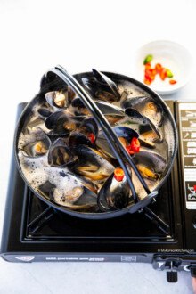Boiling mussel soup in a black pot.