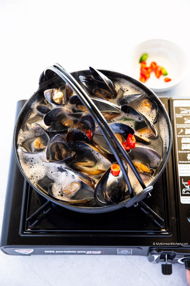 Boiling mussel soup in a black pot.