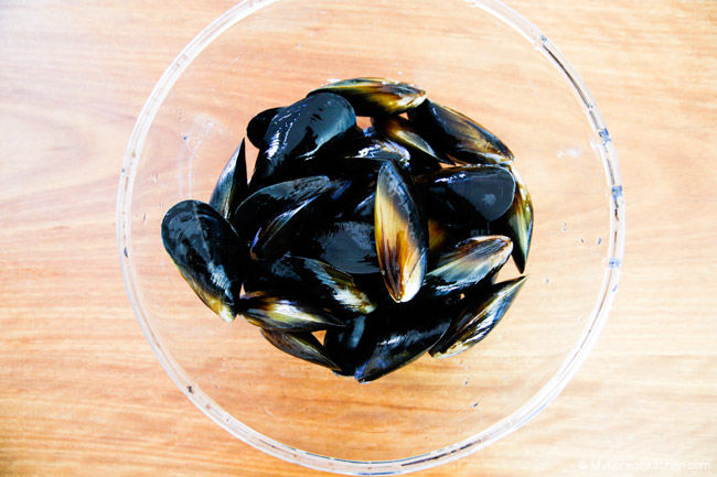 Cleaned mussels placed in a clear bowl on the bench.