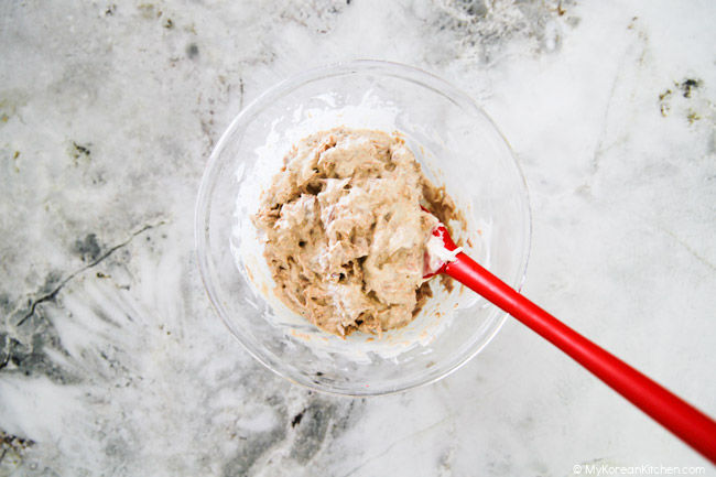 Mixing tuna and mayo in a bowl with a red spatula.