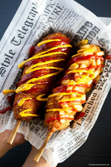 Two Korean corn dogs lay next to each other on waxed paper.