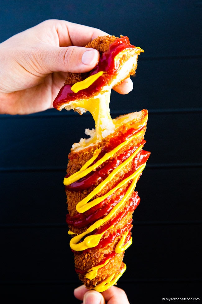 Pulling the top of a cheese corn dog with one's hands.