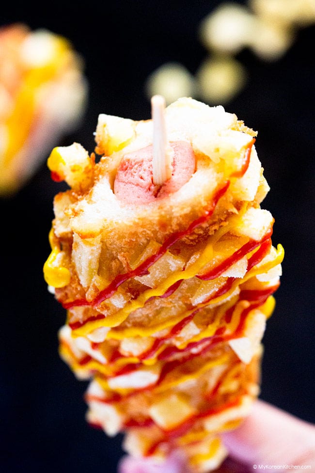 Partially eaten Korean potato-corn dog, with the top of the sausage exposed.