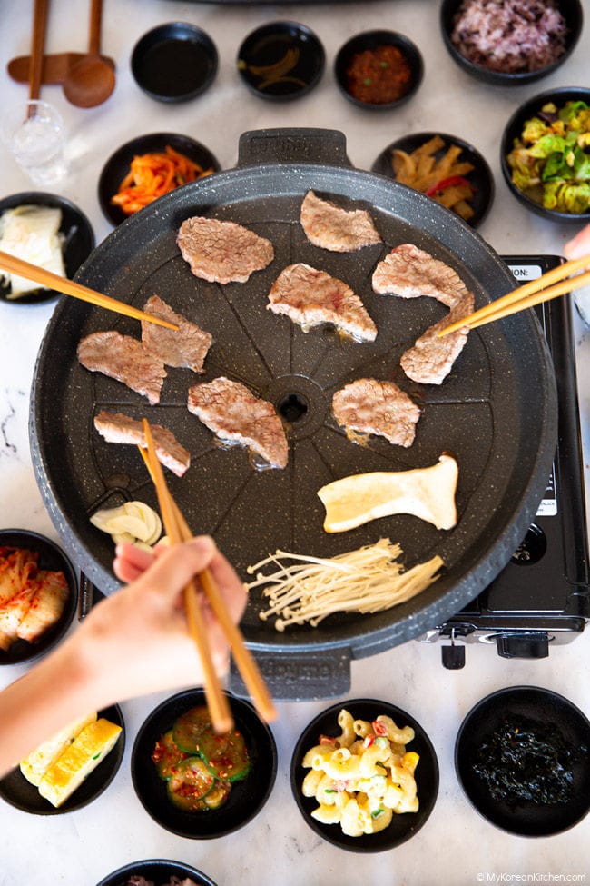 Picking up grilled Korean BBQ with a pair of wooden chopsticks.