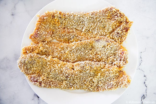 Three slices of panko-breaded donkatsu on a white plate.