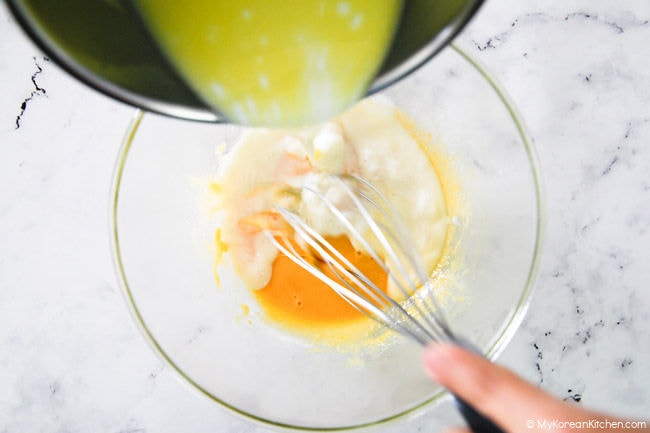 Combining warmed-up milk with egg yolk mixture.