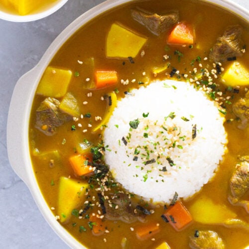Korean curry is presented encircling a mound of rice in a ribbed plate.