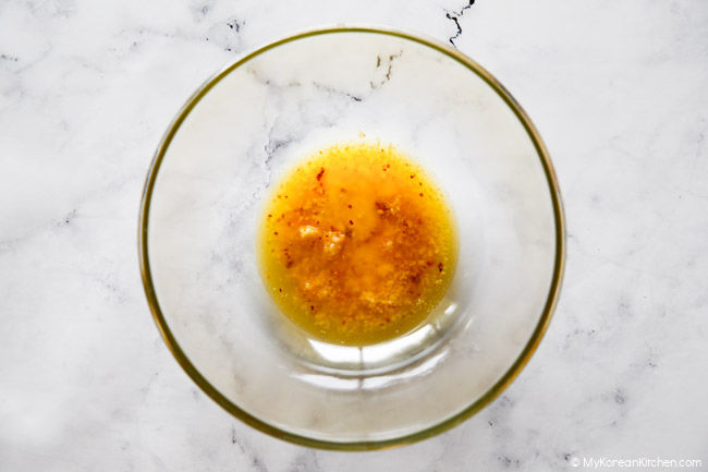 Melted butter and other garlic custard ingredients in a clear medium-sized bowl.