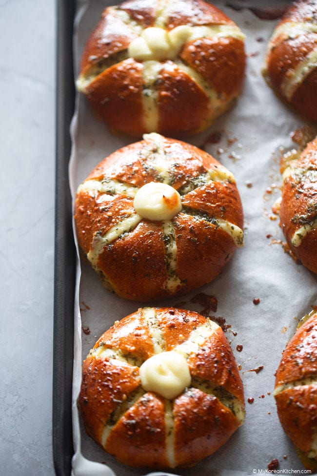 Baked cream cheese garlic bread on a baking tray, highlighting three cream cheese garlic buns.