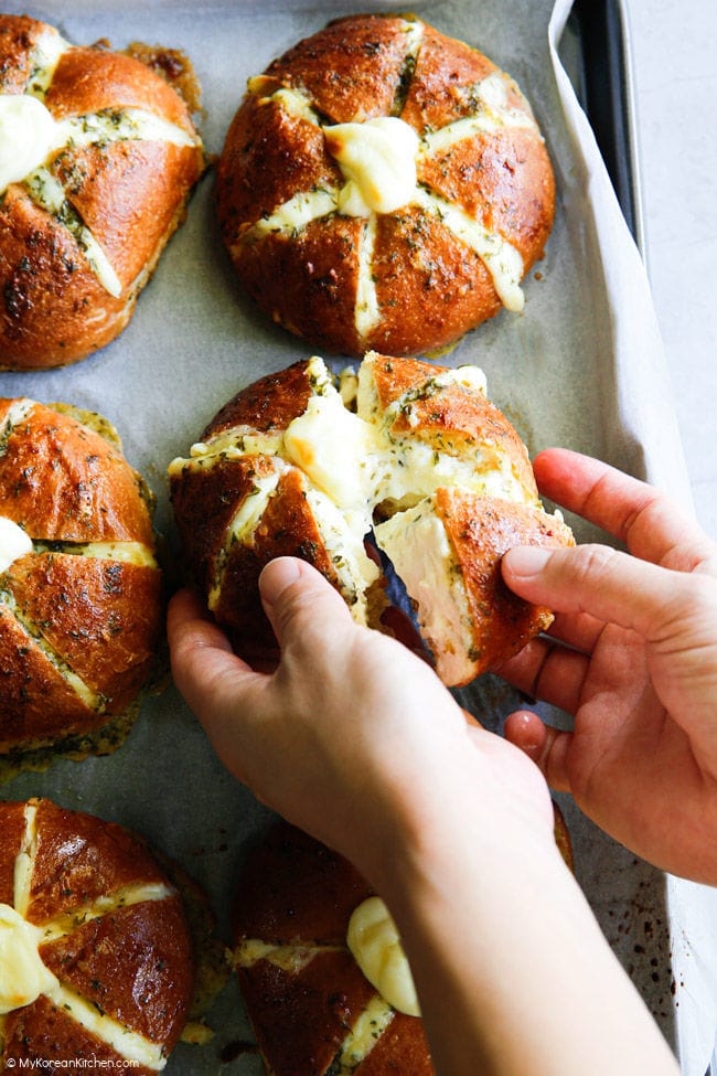 Pulling apart a section of cream cheese garlic bread with hands.