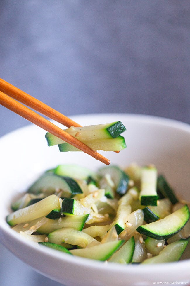 Holding stir-fried zucchini with chopsticks.