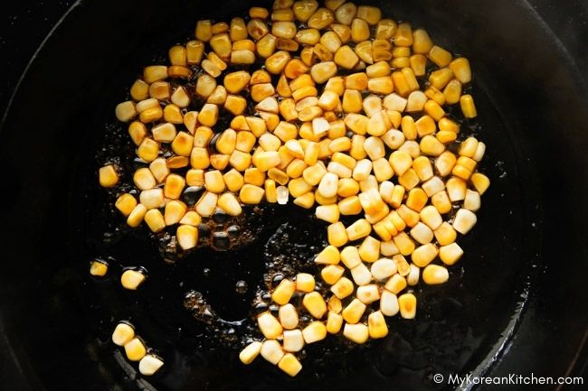 Stir-frying corn kernels in a skillet.