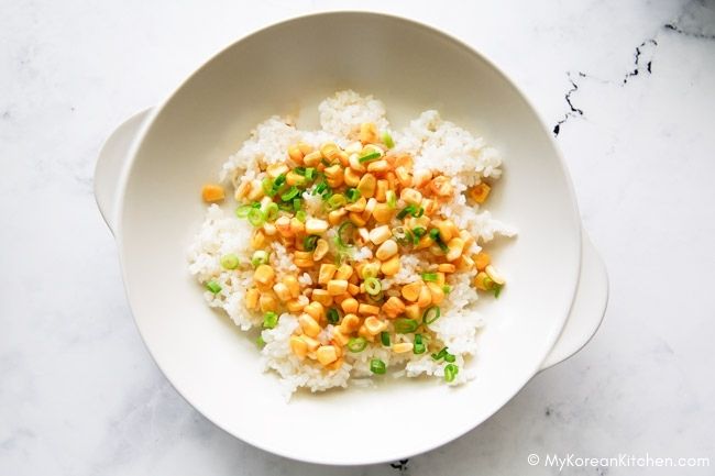 Assembling rice, corn, and green onions in a shallow bowl for serving.