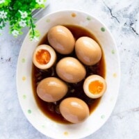 Marinated eggs served on an oval plate with savory sauce.
