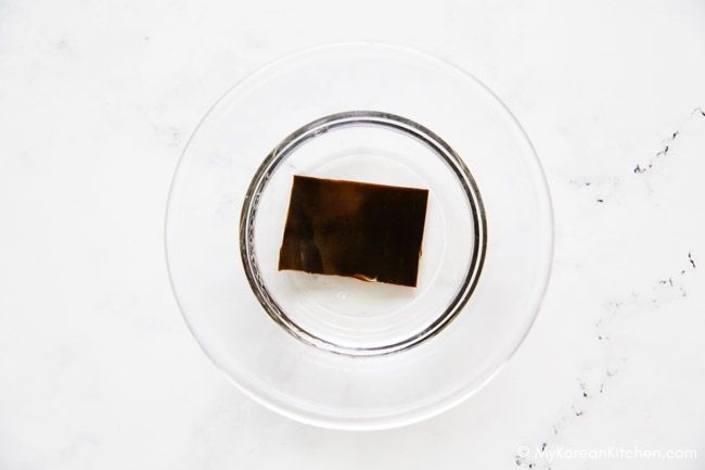 A close-up of soaking dried kelp in a bowl of water to rehydrate.