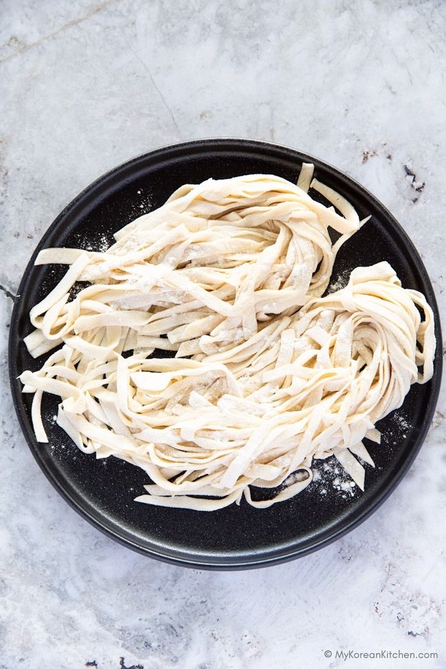 Finished knife-cut noodles on a black round plate, ready to serve