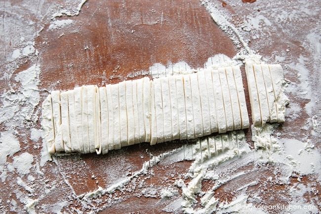 Sliced knife-cut noodles on a floured cutting board