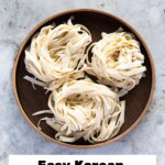 Three bundles of knife-cut noodles placed on a round wooden plate