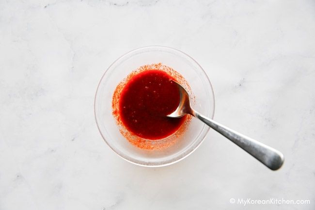 A spoon is in a bowl of sauce.